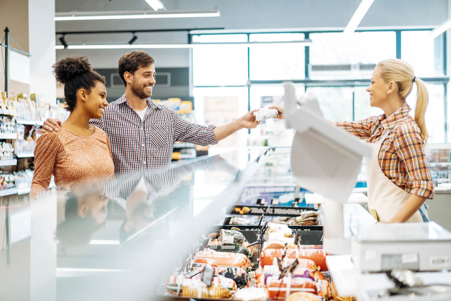 Employee in supermarket serving customers at butcher’s department